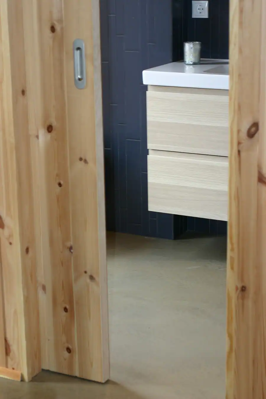 Rennihurð úr furu inn á baðherbergi með bláum vegg